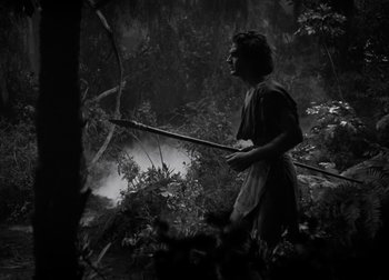 Movie still from “One Million B.C.” (1940), directed by Hal Roach Jr. – A woman is holding a bow and arrow in the woods; Wide shot, High angle