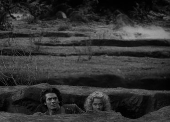 Movie still from “One Million B.C.” (1940), directed by Hal Roach Jr. – A man and a woman sitting on a rock in a field; Wide shot, High angle
