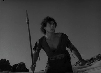 A man holding a spear while standing on a beach
