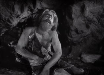 Movie still from “One Million B.C.” (1940), directed by Hal Roach Jr. – An old man sitting on the ground in a cave; Medium shot, High angle