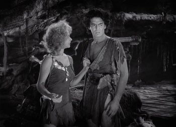 Movie still from “One Million B.C.” (1940), directed by Hal Roach Jr. – A man and a woman standing next to each other in a cave; Medium shot, Over the shoulder angle