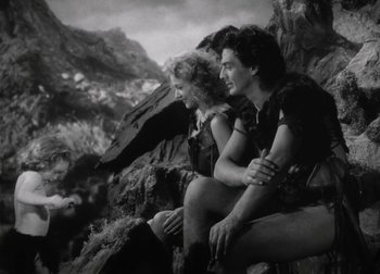 Movie still from “One Million B.C.” (1940), directed by Hal Roach Jr. – A man and a woman sitting next to each other on top of a hill; Wide shot, Low angle
