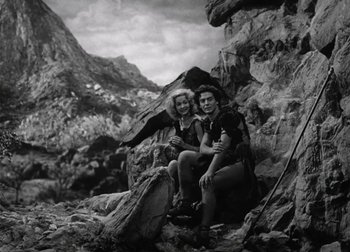 Movie still from “One Million B.C.” (1940), directed by Hal Roach Jr. – A man and a woman sitting on top of a rock; Wide shot, Low angle