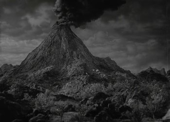 Movie still from “One Million B.C.” (1940), directed by Hal Roach Jr. – A black and white photo of a volcano with smoke coming from it; Extreme Wide shot, High angle
