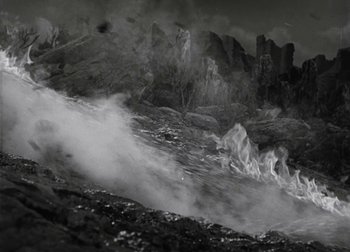 Movie still from “One Million B.C.” (1940), directed by Hal Roach Jr. – A black - and - white photo of a mountain with smoke coming out of it; Extreme Wide shot, High angle