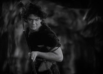 Movie still from “One Million B.C.” (1940), directed by Hal Roach Jr. – Black and white photograph of a man holding an umbrella; Medium shot, Low angle