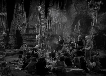 Movie still from “One Million B.C.” (1940), directed by Hal Roach Jr. – A group of people sitting around in a cave; Wide shot, High angle