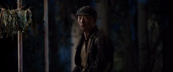 Movie still from “One Second” (2020), directed by Yimou Zhang – A man wearing a hat and a leather jacket; Medium shot, Over the shoulder angle