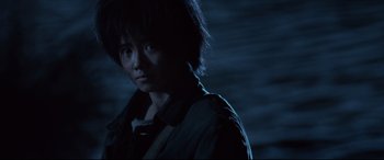 Movie still from “One Second” (2020), directed by Yimou Zhang – A person with short black hair standing in the dark; Close Up shot, Low angle