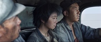 Movie still from “One Second” (2020), directed by Yimou Zhang – A man sitting next to another man in a car; Close Up shot, Over the shoulder angle