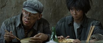 Movie still from “One Second” (2020), directed by Yimou Zhang – A man and a woman sitting at a dinner table; Close Up shot, Over the shoulder angle