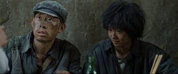 Movie still from “One Second” (2020), directed by Yimou Zhang – Two men sitting next to each other with a bottle of beer; Close Up shot, Over the shoulder angle