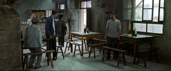 Movie still from “One Second” (2020), directed by Yimou Zhang – A group of people standing around a table; Wide shot, High angle
