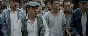 Movie still from “One Second” (2020), directed by Yimou Zhang – A group of men standing next to each other; Medium shot, High angle