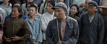 Movie still from “One Second” (2020), directed by Yimou Zhang – A group of people standing in front of each other; Medium shot, Over the shoulder angle