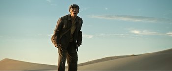 Movie still from “One Second” (2020), directed by Yimou Zhang – A man standing on top of a sand dune; Medium shot, Low angle