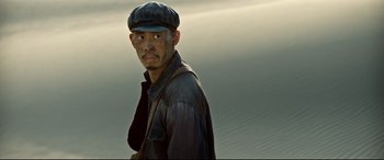 Movie still from “One Second” (2020), directed by Yimou Zhang – A man wearing a hat and a leather jacket; Close Up shot, Low angle