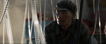 Movie still from “One Second” (2020), directed by Yimou Zhang – A man wearing a hat and looking at the camera; Close Up shot, Low angle