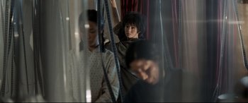 Movie still from “One Second” (2020), directed by Yimou Zhang – A woman sitting on top of a bus with other people behind it; Medium shot, Low angle