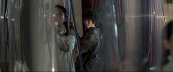 Movie still from “One Second” (2020), directed by Yimou Zhang – A group of people standing next to each other in a room; Medium shot, Low angle