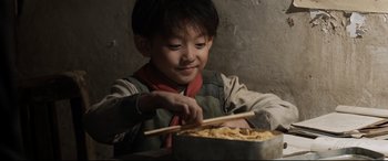 Movie still from “One Second” (2020), directed by Yimou Zhang – A young boy holding chopsticks over a bowl of noodles; Close Up shot, High angle