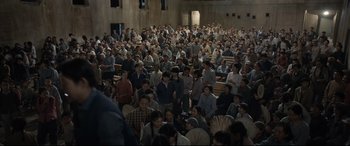 Movie still from “One Second” (2020), directed by Yimou Zhang – A large group of people sitting in a large room; Extreme Wide shot, High angle