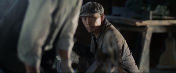 Movie still from “One Second” (2020), directed by Yimou Zhang – A man wearing a hat and gloves looking at the camera; Close Up shot, Low angle