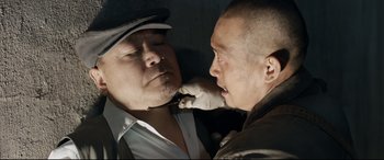 Movie still from “One Second” (2020), directed by Yimou Zhang – Two men in hats are touching each other's face; Close Up shot, Overhead angle