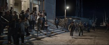 Movie still from “One Second” (2020), directed by Yimou Zhang – A group of people standing on some steps at night; Wide shot, High angle