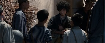 Movie still from “One Second” (2020), directed by Yimou Zhang – A group of young men standing next to each other; Medium shot, Over the shoulder angle