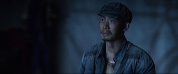 Movie still from “One Second” (2020), directed by Yimou Zhang – A man wearing a hat and a jacket; Close Up shot, Low angle