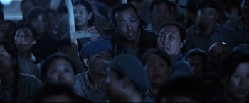 Movie still from “One Second” (2020), directed by Yimou Zhang – A group of people standing next to each other; Medium shot, Over the shoulder angle