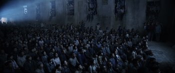 Movie still from “One Second” (2020), directed by Yimou Zhang – A large group of people sitting in a room; Wide shot, High angle
