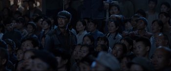 Movie still from “One Second” (2020), directed by Yimou Zhang – A group of people sitting in a room at night; Medium shot, Over the shoulder angle