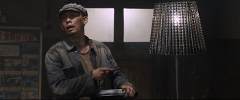 Movie still from “One Second” (2020), directed by Yimou Zhang – A man wearing a hat and jacket is holding a steering wheel; Medium shot, Low angle