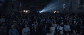 Movie still from “One Second” (2020), directed by Yimou Zhang – A crowd of people sitting in a dark room; Wide shot, High angle