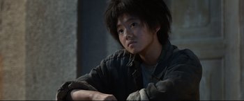 Movie still from “One Second” (2020), directed by Yimou Zhang – A young man with a shaggy black hair sitting in a room; Close Up shot, Over the shoulder angle