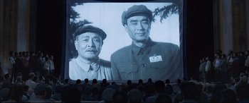Movie still from “One Second” (2020), directed by Yimou Zhang – People watching a movie with a picture of two men; Medium shot, Low angle