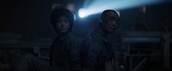 Movie still from “One Second” (2020), directed by Yimou Zhang – A man and a woman standing next to each other in the dark; Medium shot, Low angle