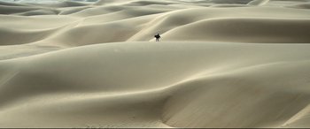 Movie still from “One Second” (2020), directed by Yimou Zhang – A person standing on top of a sand dune; Extreme Wide shot, High angle