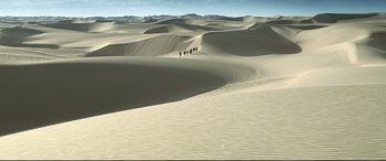 Movie still from “One Second” (2020), directed by Yimou Zhang – A group of people walking across a sand dune; Extreme Wide shot, High angle