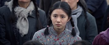 Movie still from “One Second” (2020), directed by Yimou Zhang – A girl with pigtails is looking at the camera; Close Up shot, Over the shoulder angle