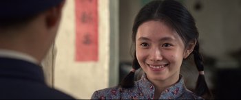 Movie still from “One Second” (2020), directed by Yimou Zhang – A young woman smiles brightly at the camera; Close Up shot, Over the shoulder angle