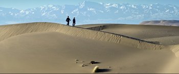 Movie still from “One Second” (2020), directed by Yimou Zhang – Two men are standing on a sand dune; Extreme Wide shot, High angle