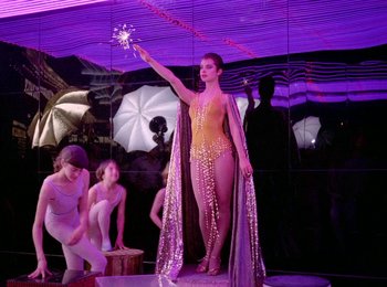 Movie still from “One from the Heart” (1981), directed by Francis Ford Coppola – A woman standing in front of two other women holding umbrellas; Wide shot, Low angle