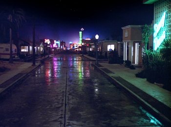 Movie still from “One from the Heart” (1981), directed by Francis Ford Coppola – A wet street with neon lights on the side of the road; Extreme Wide shot, High angle