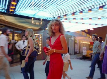 Movie still from “One from the Heart” (1981), directed by Francis Ford Coppola – A woman in a red dress is holding a red purse; Wide shot, Low angle