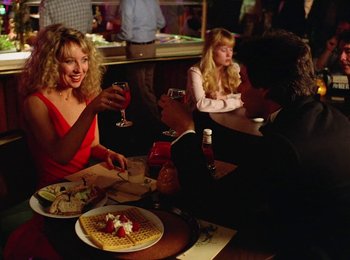 Movie still from “One from the Heart” (1981), directed by Francis Ford Coppola – A group of people sitting at a table with food; Medium shot, Low angle