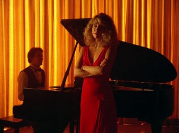 Movie still from “One from the Heart” (1981), directed by Francis Ford Coppola – A woman in a red dress standing in front of a piano; Medium shot, Low angle