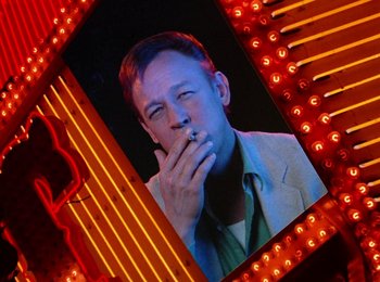 Movie still from “One from the Heart” (1981), directed by Francis Ford Coppola – A man smoking a cigarette in front of a neon sign; Close Up shot, Low angle